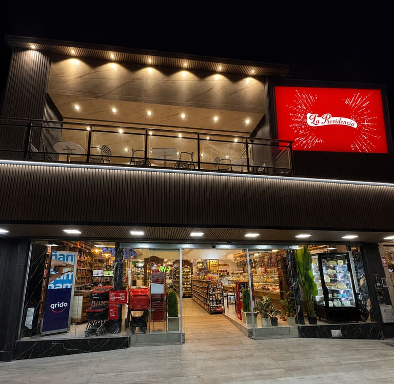 Sucursal Avellaneda iluminada de noche, con el cartel rojo de La Providencia encendido